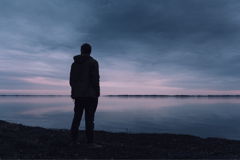 Silhouette einer Person blickt über eine weite Landschaft bei Sonnenuntergang – symbolisiert Weitblick, Zielstrebigkeit und Orientierung.
