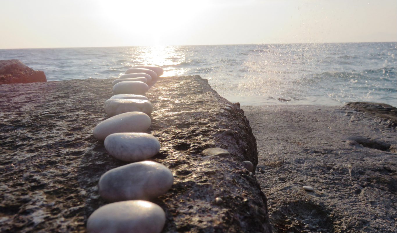 Runde Steine bilden einen Weg über das Wasser in Richtung Horizont – symbolisiert visionären Fortschritt und Verantwortung.